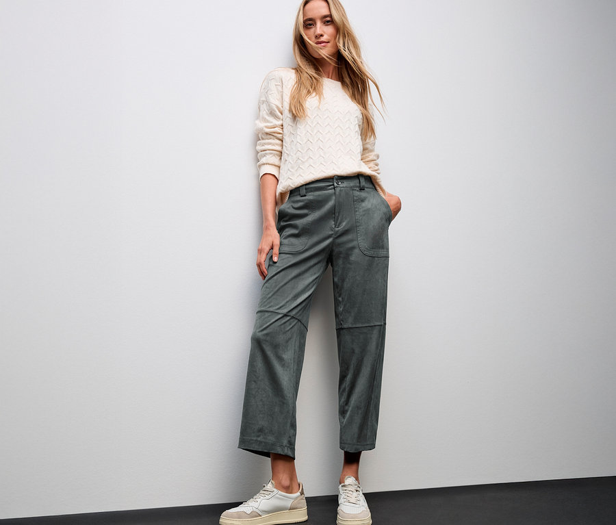 Femme posant en pull crème et pantalon de velours vert Straight Leg Street One et baskets blanches.