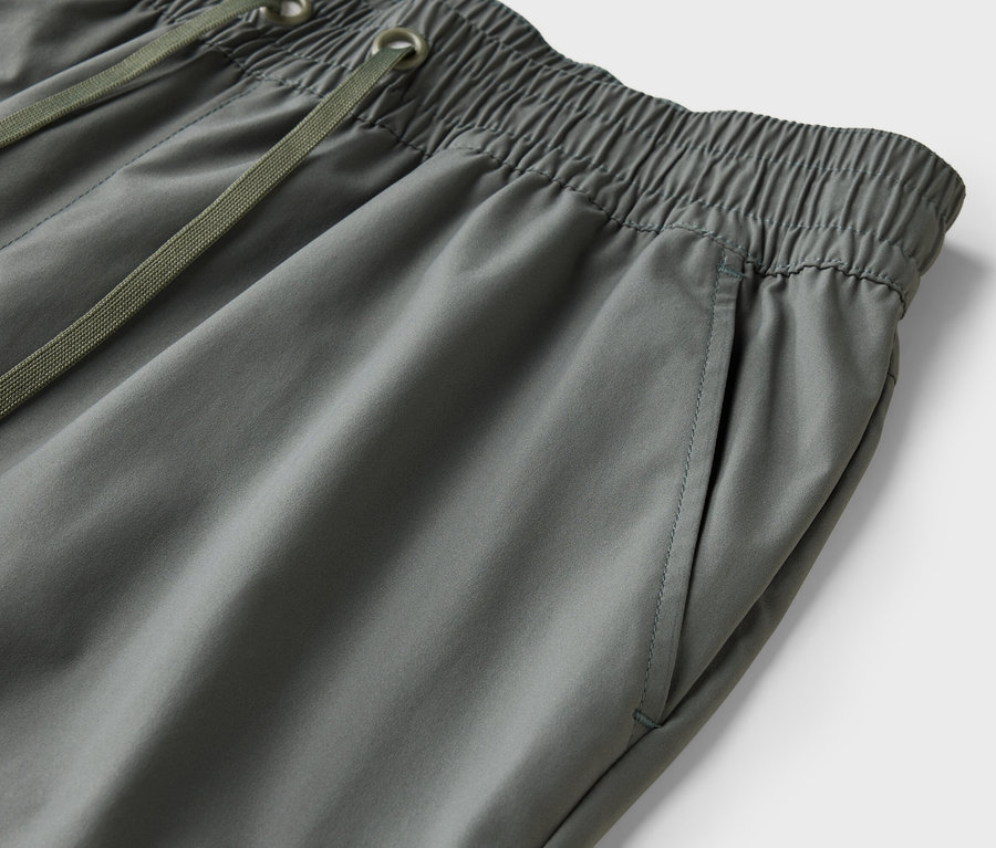 Gros plan d'un pantalon gris avec cordon de serrage et taille élastique.