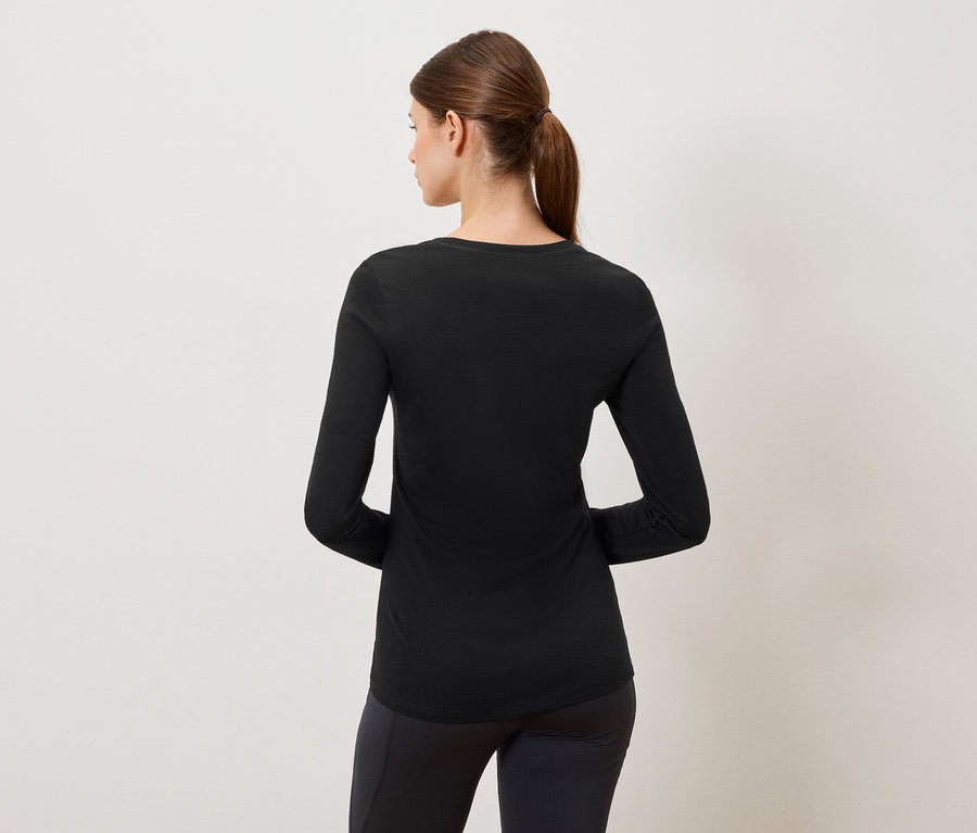 Vue de dos d'une femme portant un t-shirt noir à manches longues et un legging noir sur un fond neutre.
