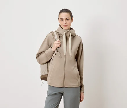Femme portant un sac à dos et un sweat à capuche zippé