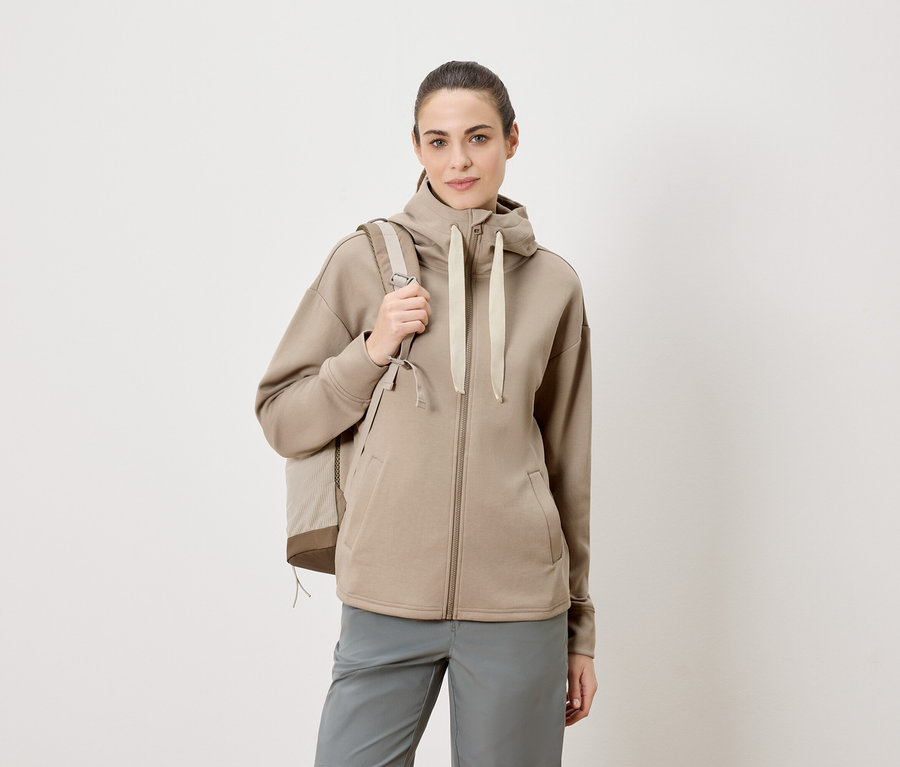 Femme portant un sac à dos et un sweat à capuche zippé