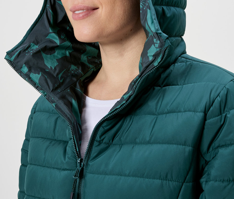 Femme portant une doudoune verte à capuche avec fermeture éclair et motif floral.