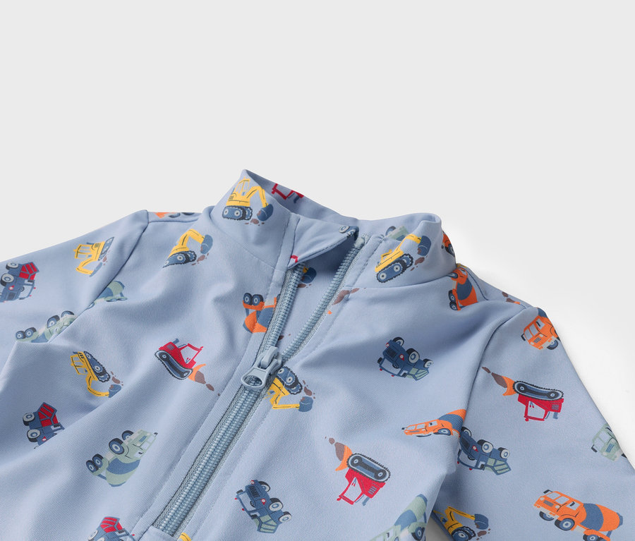 Tissu bleu clair zippé avec des motifs de camions de chantier multicolores.