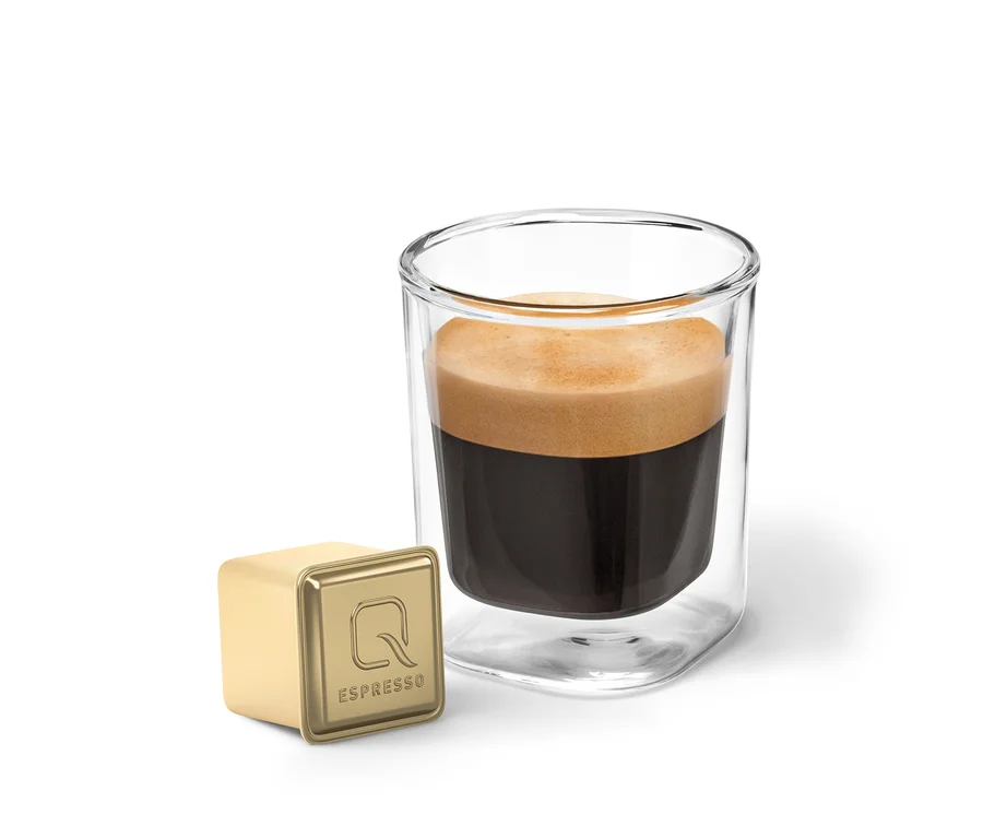 Un verre d'espresso et une capsule dorée Qbo Flavoured Espresso Raspberry White Choc.