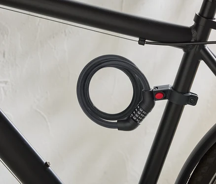 Un vélo noir est équipé d'un antivol à câble spiralé avec un code numérique fixé au cadre.