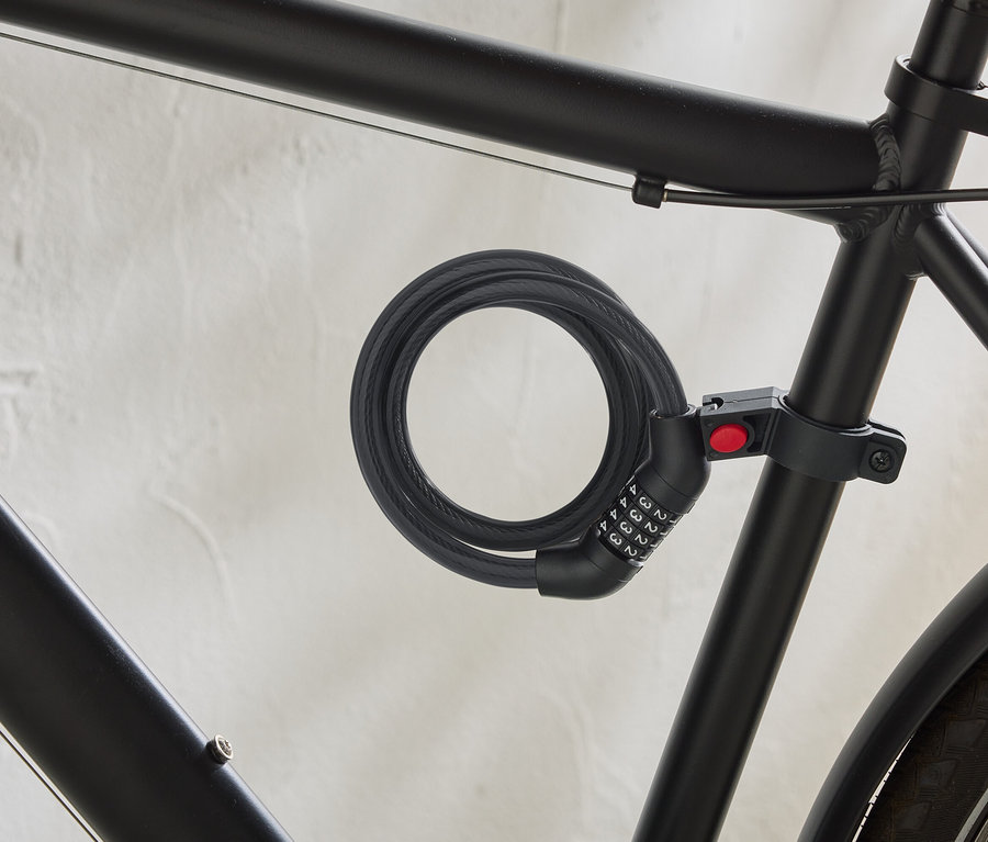 Un vélo noir est équipé d'un antivol à câble spiralé avec un code numérique fixé au cadre.