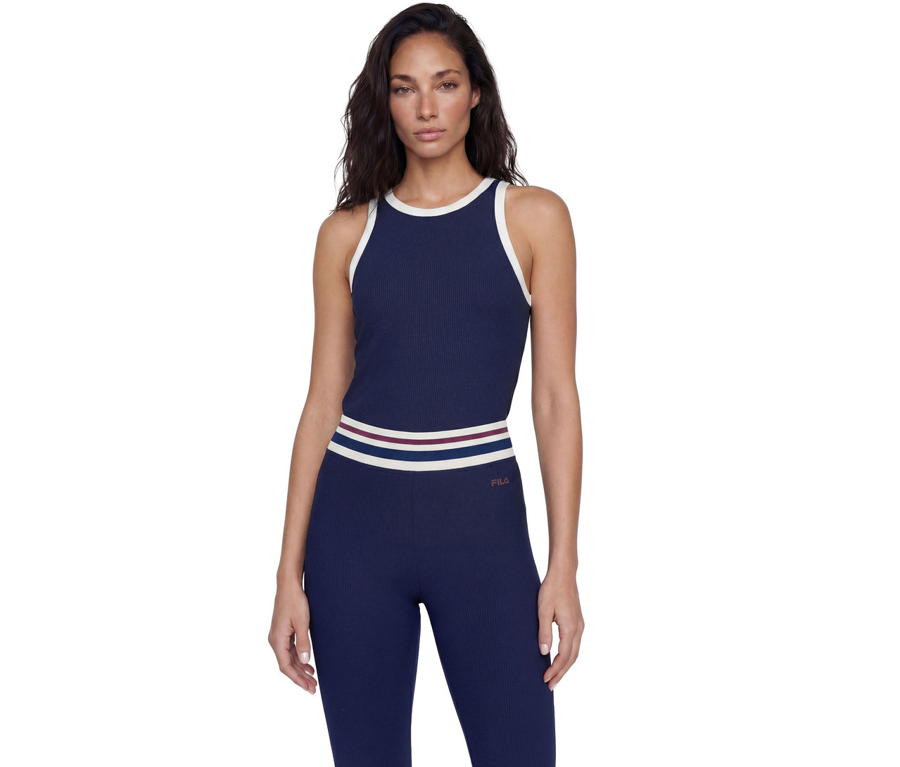 Femme portant un débardeur côtelé bleu marine avec des bordures blanches et un legging assorti avec une ceinture rayée, affichant le logo Fila sur la hanche.