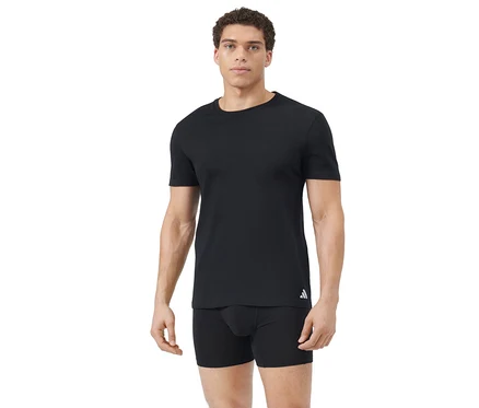 Homme aux cheveux courts et bouclés portant un t-shirt noir uni avec un logo blanc sur la hanche gauche et un boxer noir, sur fond blanc.