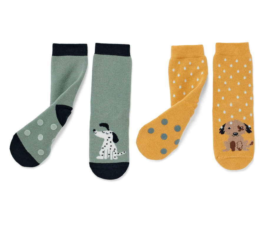 Deux paires de chaussettes anti-dérapantes pour enfant : une paire verte avec un motif de dalmatien, une paire jaune avec un motif de chiot.