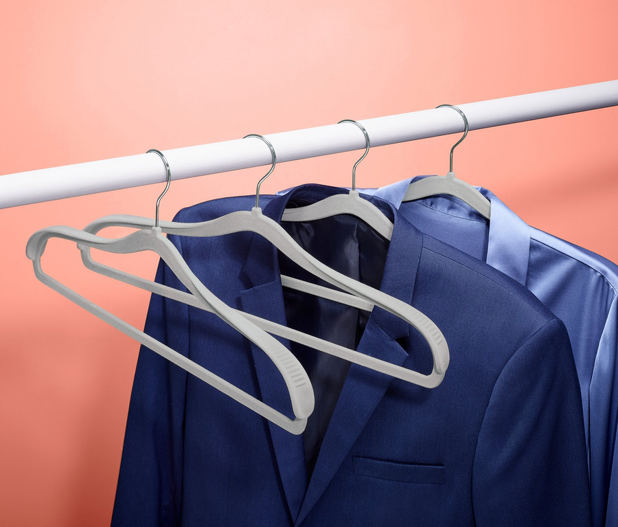Deux costumes bleus suspendus à une barre blanche sur 4 cintres avec renfort aux épaules.