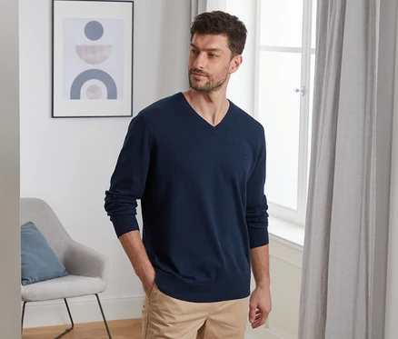 Un homme pose en pull en lin bleu marine.
