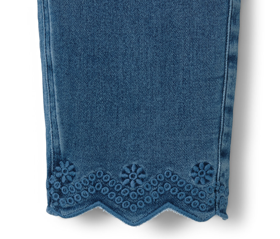 Détail d'un tregging 7/8 bleu avec broderie ajourée à l'ourlet.