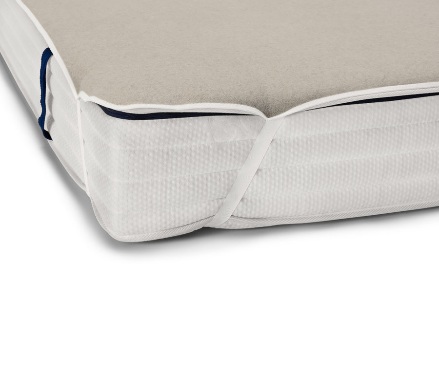 Détail du coin d'un matelas avec un surmatelas beige avec du lin.