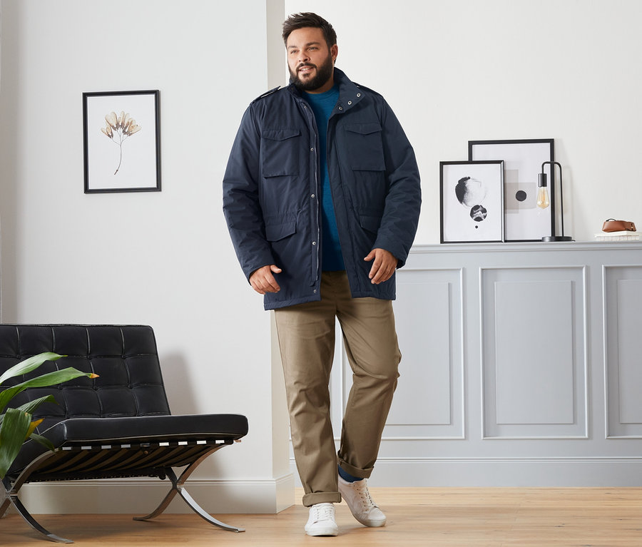 Un homme portant une veste Field bleue, un pull en laine mérinos bleu, un pantalon chino caramel et 4 paires de chaussettes en laine mérinos bleu foncé, rouges et vert foncé.