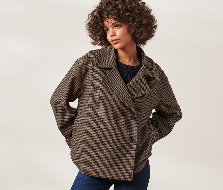 Femme posant dans une veste à carreaux avec de la laine et un jean bleu.
