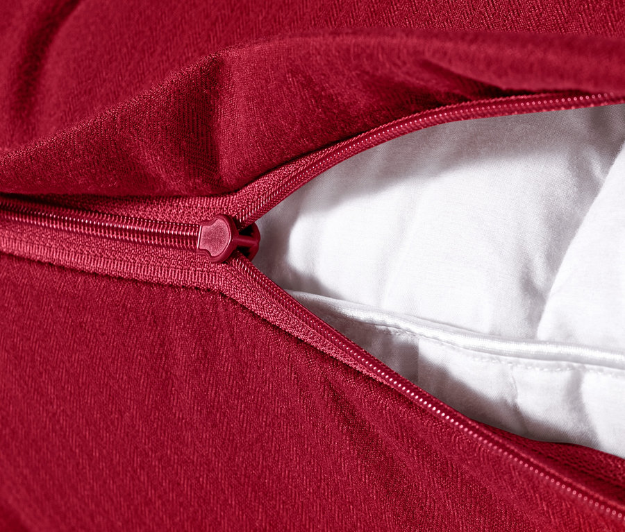 Gros plan d'une housse de coussin rouge en flanelle microfibre (env. 80 x 40 cm) avec une fermeture éclair ouverte, révélant le rembourrage blanc.