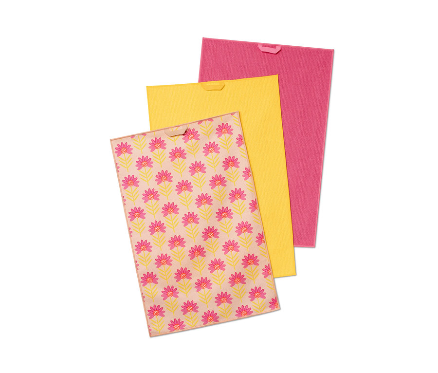 Trois linges de cuisine : un à motif floral, un jaune et un rose.