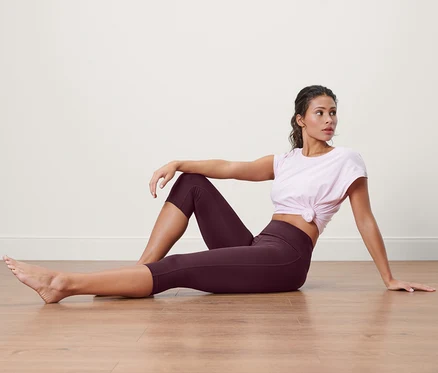 Femme assise par terre portant un corsaire de sport et un t-shirt.