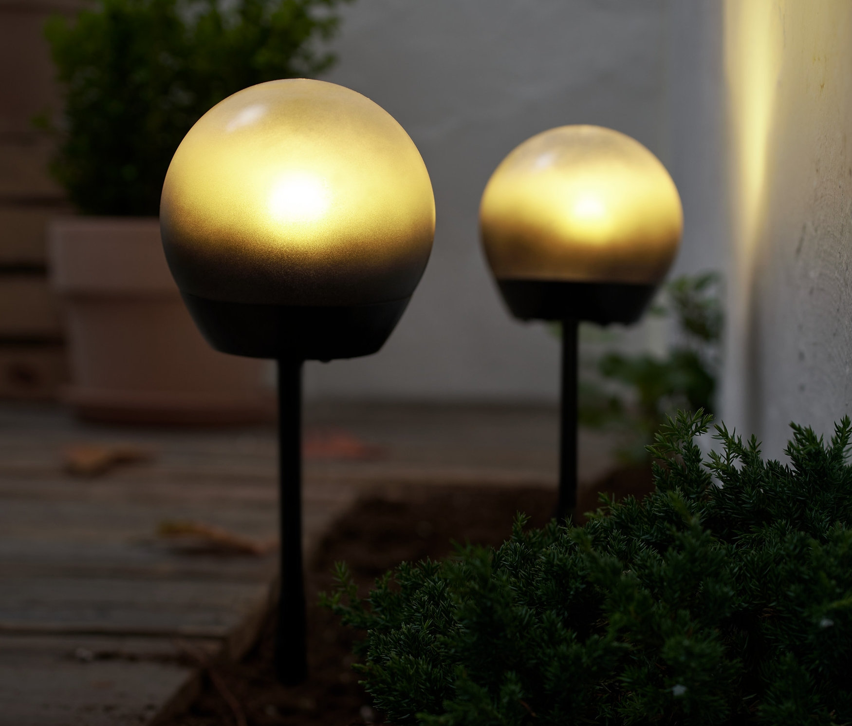 Deux lampes sphériques à LED illuminent le sol à l'extérieur.