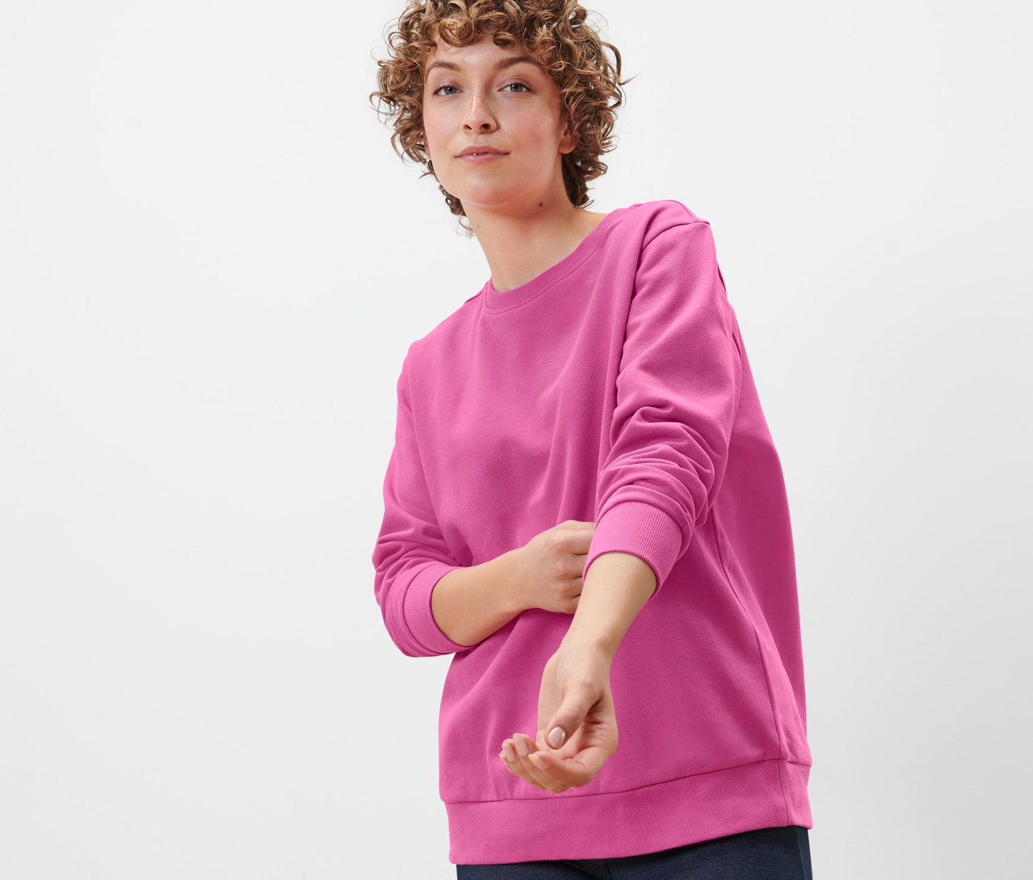 Femme posant dans un sweat-shirt rose vif.
