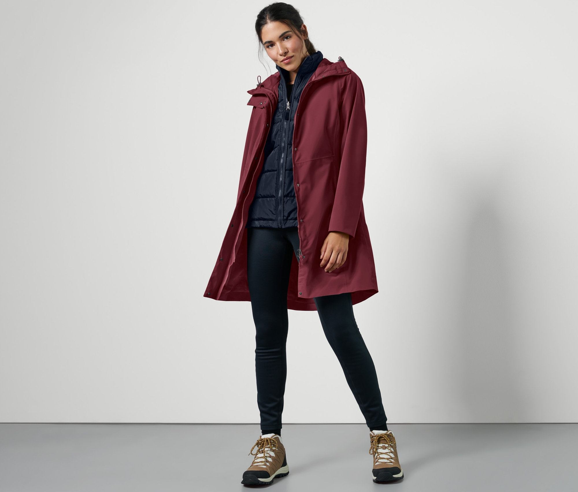 Femme posant dans un manteau d’extérieur 3 en 1 avec gilet rouge.