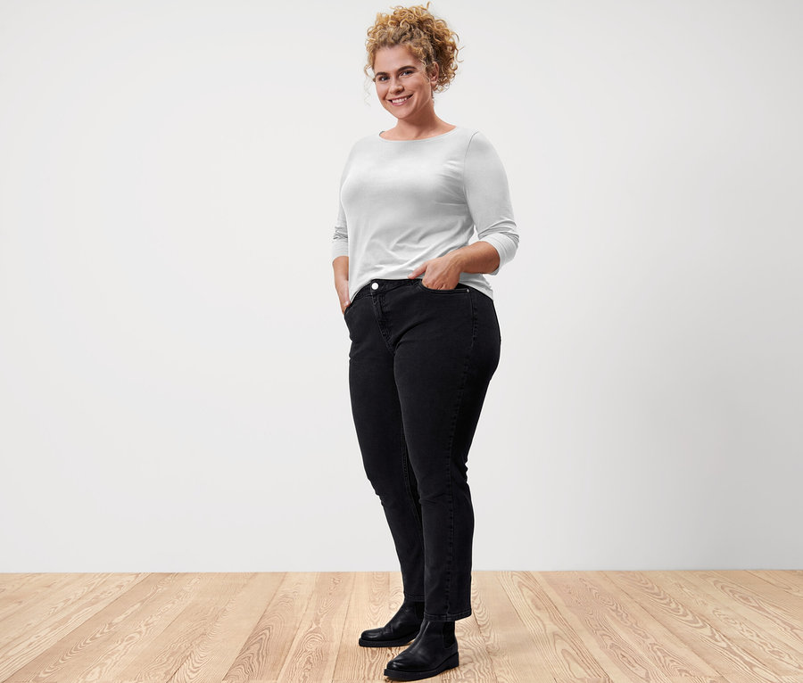 Femme posant en t-shirt blanc manches 3/4 et jean noir.