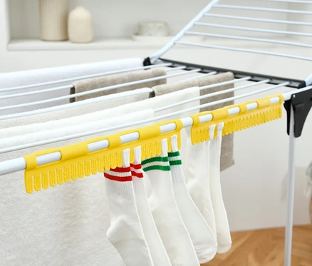 Des chaussettes blanches sont suspendues à 2 Séchoirs à chaussettes jaunes sur un étendoir à linge.