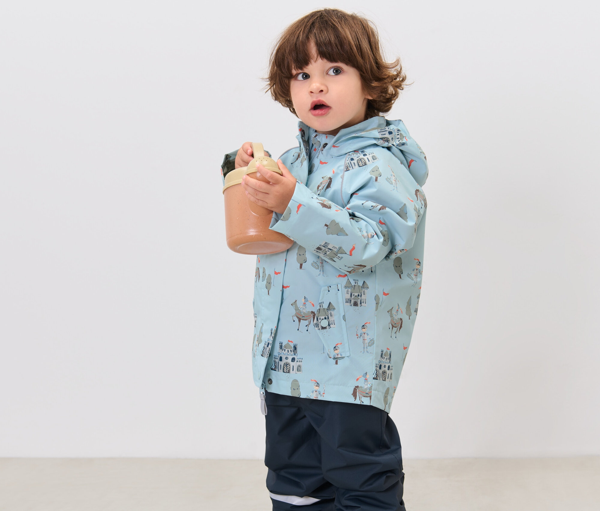 Garçon tenant une tasse et portant une veste de pluie pour enfant, chevalier.