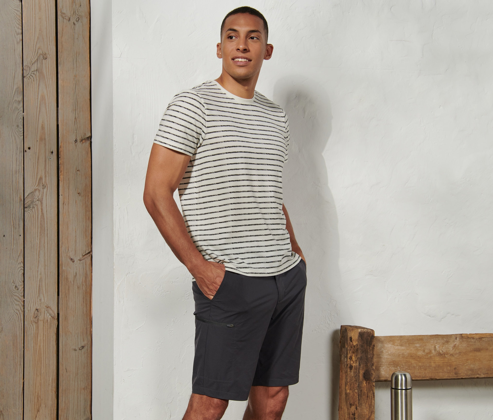 Un homme se tient debout, les mains dans les poches de son short fonctionnel en softshell.