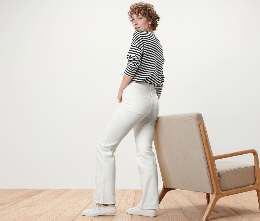 Femme regardant par-dessus son épaule et posant en jean bootcut blanc crème – Fit « Lou ».