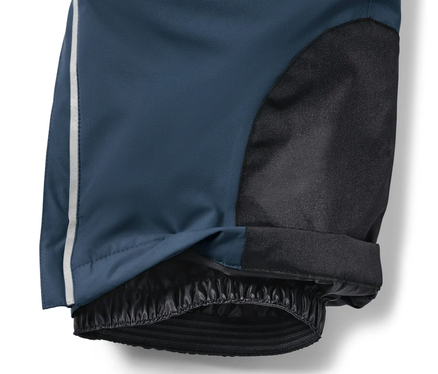 Gros plan sur un pantalon de ski bleu marine pour enfant avec un tissu noir sur le genou et une bande blanche sur le côté.