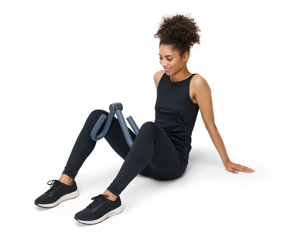 Femme assise par terre utilisant un appareil de musculation pour bras et jambes.