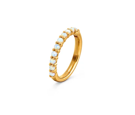 Bague dorée avec opales blanches sur fond blanc.