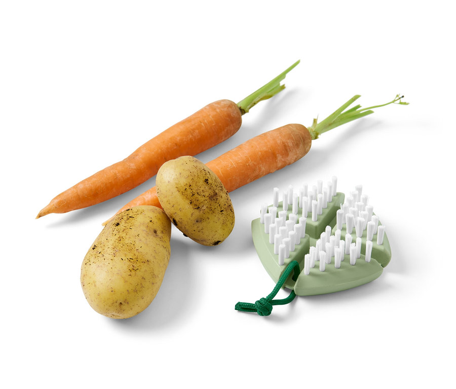 Deux carottes et deux pommes de terre sont posées l'une à côté de l'autre, à côté d'une brosse à légumes et à fruits flexible.