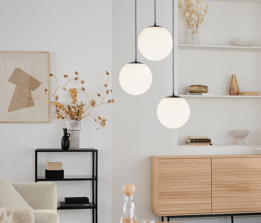 Salon avec table basse ronde, console design avec compartiments en verre et lampes à suspension avec globes en verre, 3 flammes, rondes.