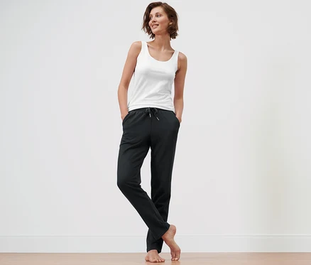 Femme debout avec les mains dans les poches d'un pantalon d’intérieur noir.