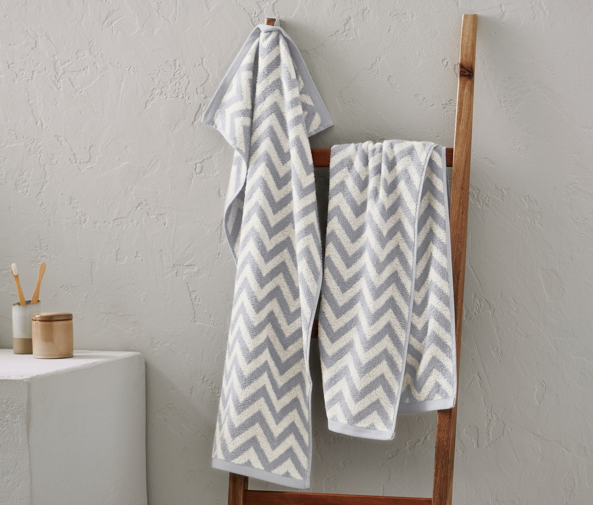 Deux torchons en jacquard gris suspendus à une échelle en bois.