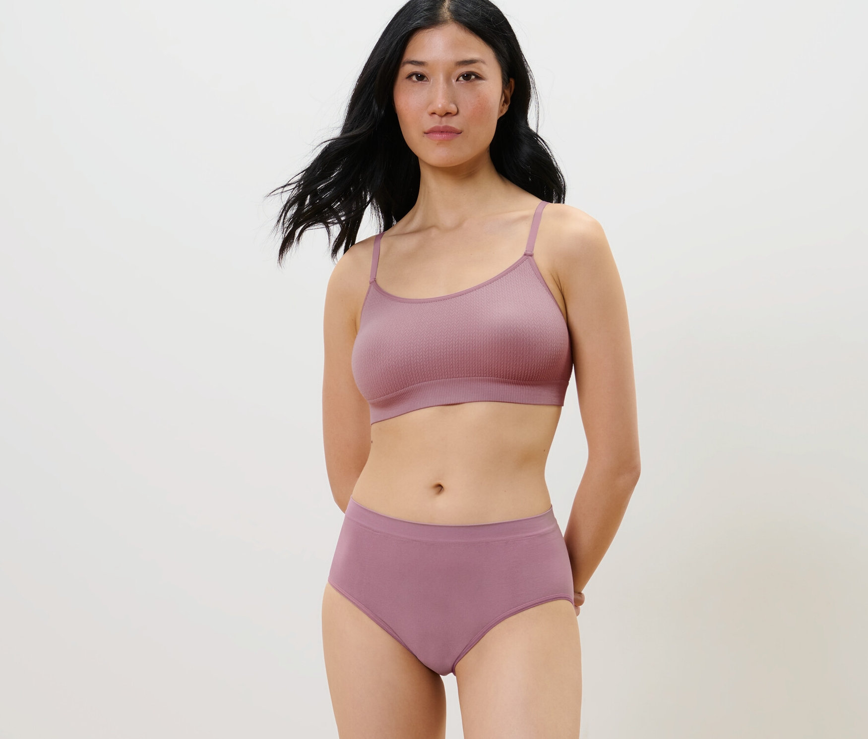 Une femme pose dans un ensemble violet sans couture avec 2 culottes sans coutures.