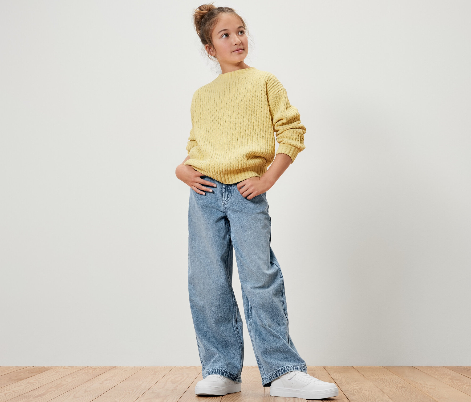 Une fille pose en pull jaune et jeans pour enfant ‒ Coupe «
Mädchen posiert in gelbem Pullover und Kinder-Jeans ‒ Fit »Lena«.