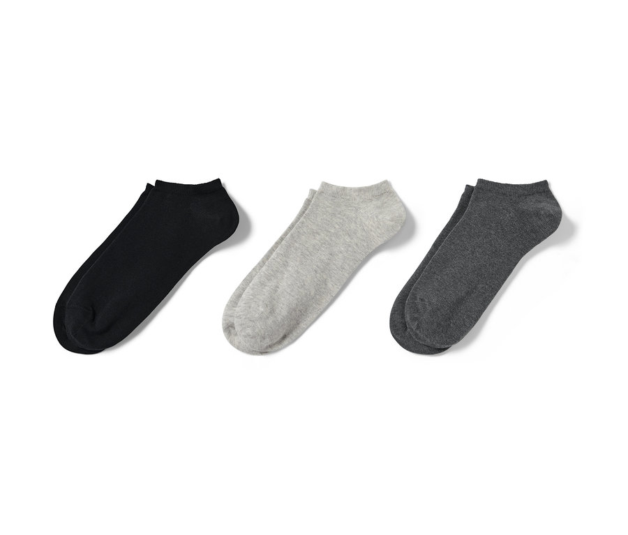 Trois paires de socquettes de sport noires, grises et gris foncé côte à côte.