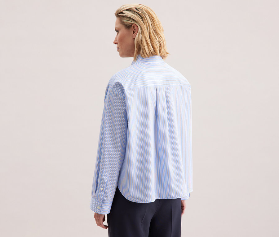 Vue arrière d'une femme blonde portant une chemise oversize rayée bleu et blanc Seidensticker.