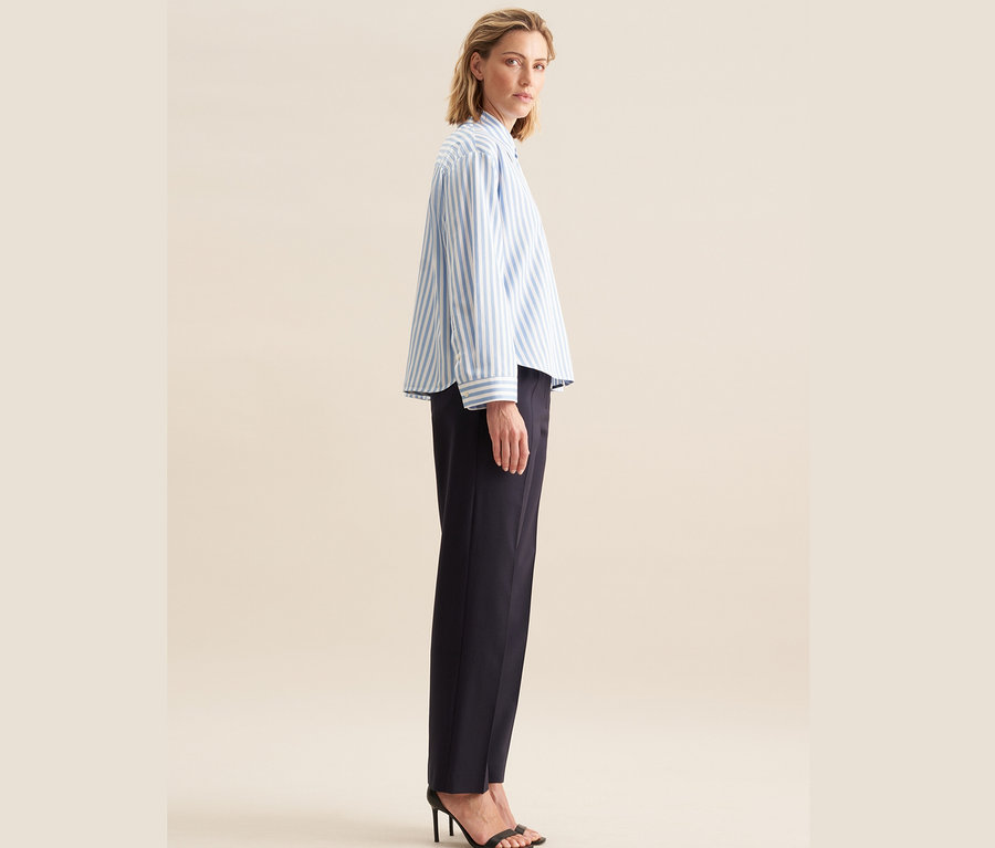 Femme posant en chemisier oversize Seidensticker, bleu et pantalon bleu foncé.