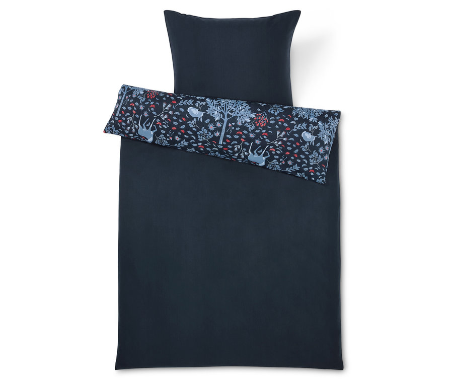 Linge de lit bleu foncé avec oreiller et coussin décoratif avec un imprimé d'arbres, de fleurs et d'animaux.