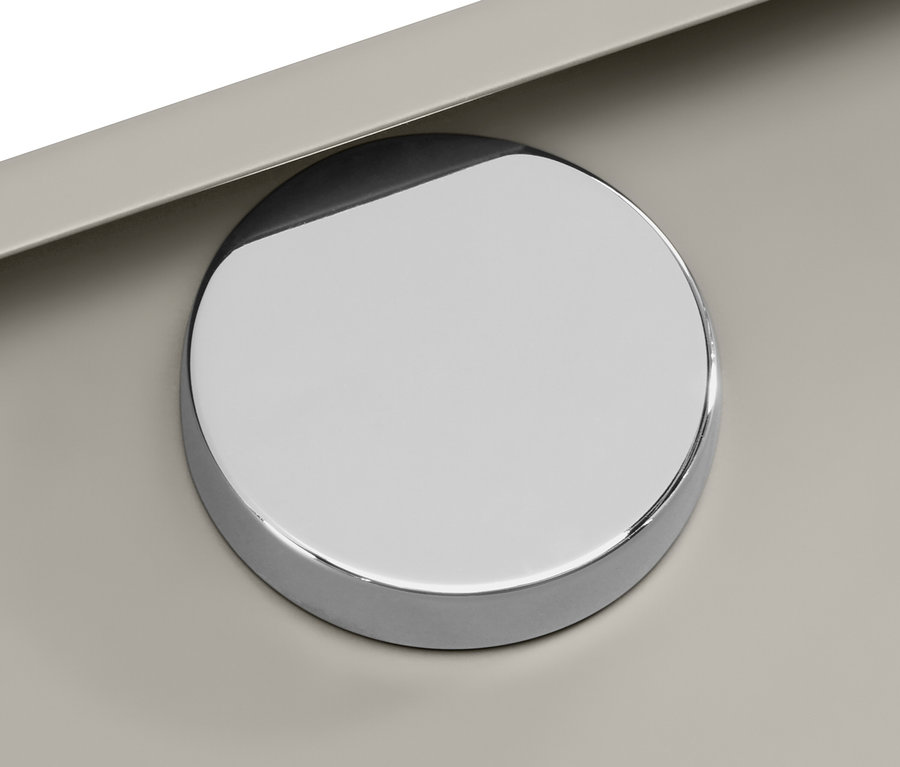 Gros plan d'un bouton rond chromé sur une surface beige.