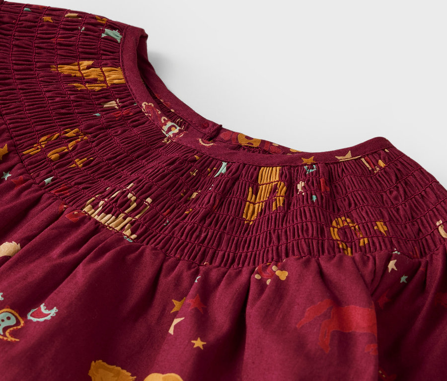 Détail d'une blouse pour enfant à motif rouge.