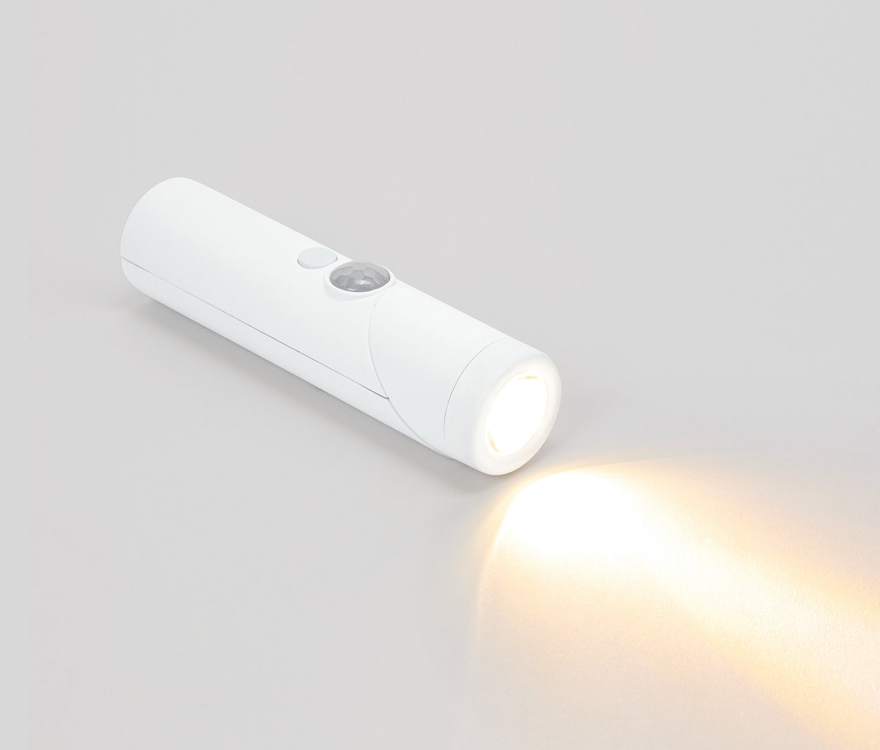 Une lampe de poche blanche brille sur un fond gris.