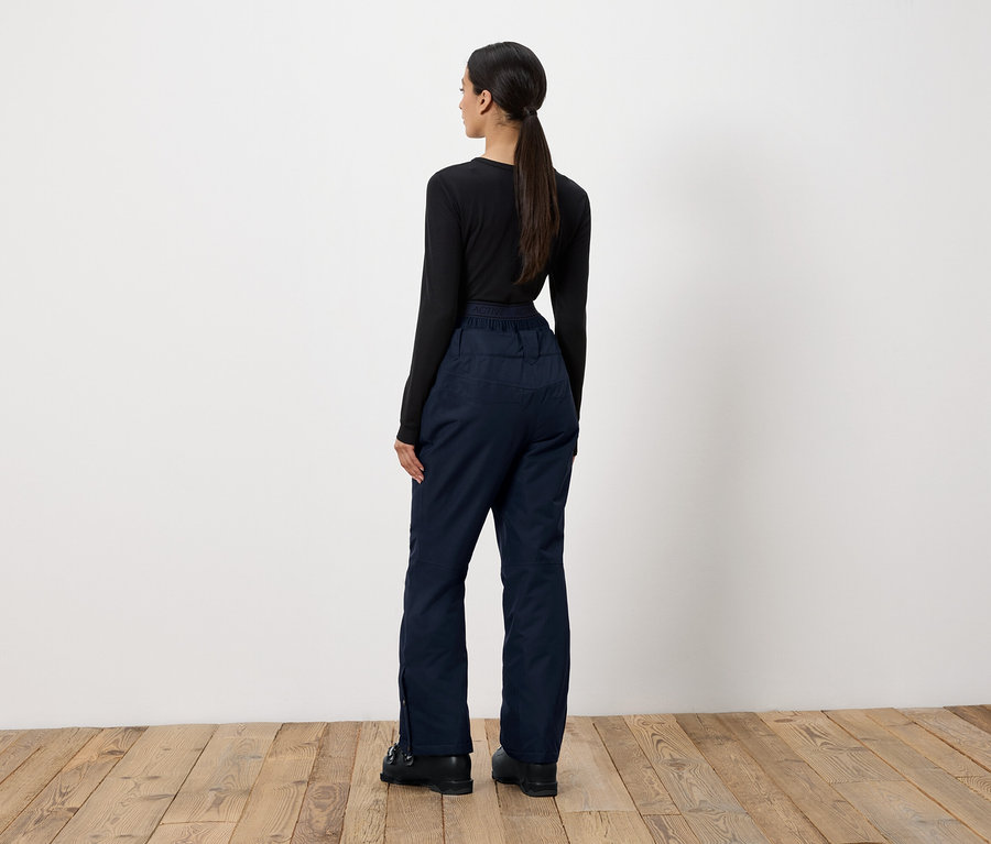 Une femme, vue de dos, porte un t-shirt noir à manches longues et un pantalon bleu marine.