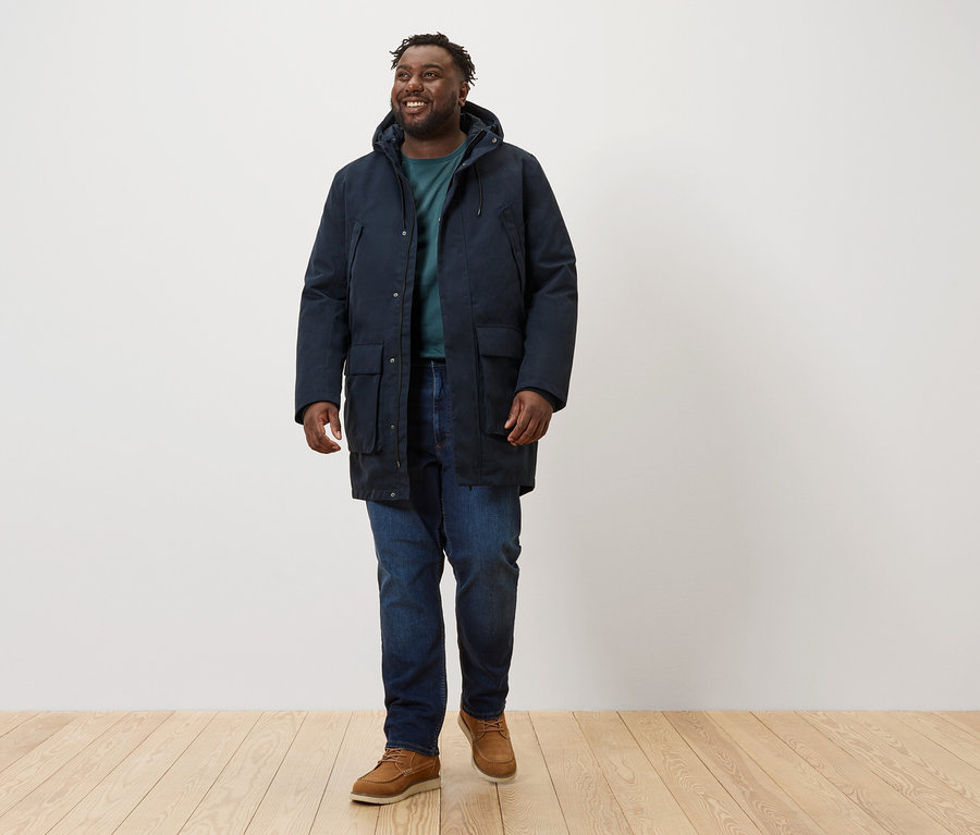 Un homme marche et porte une parka bleu marine.