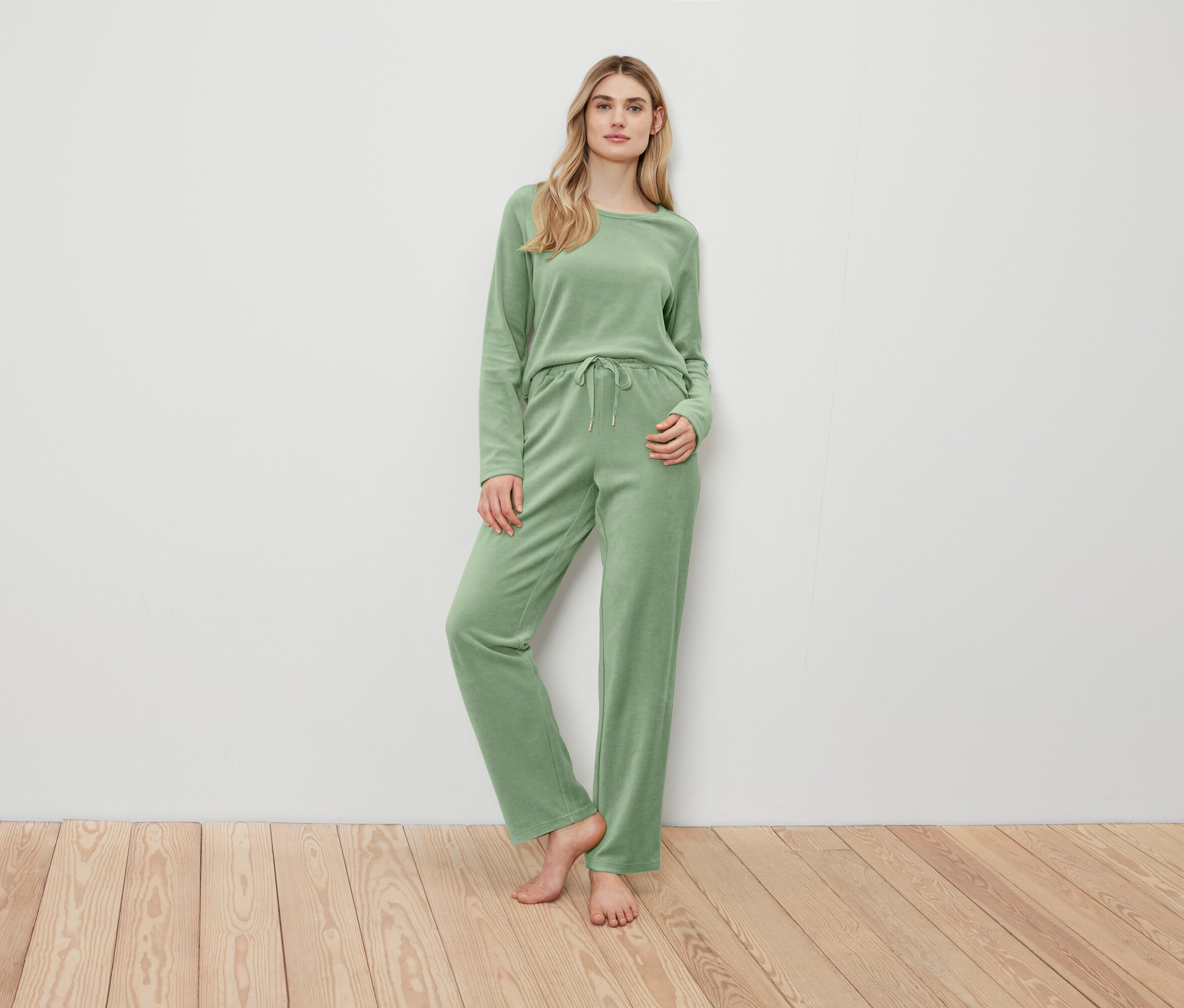 Femme posant dans un pull et un pantalon verts.