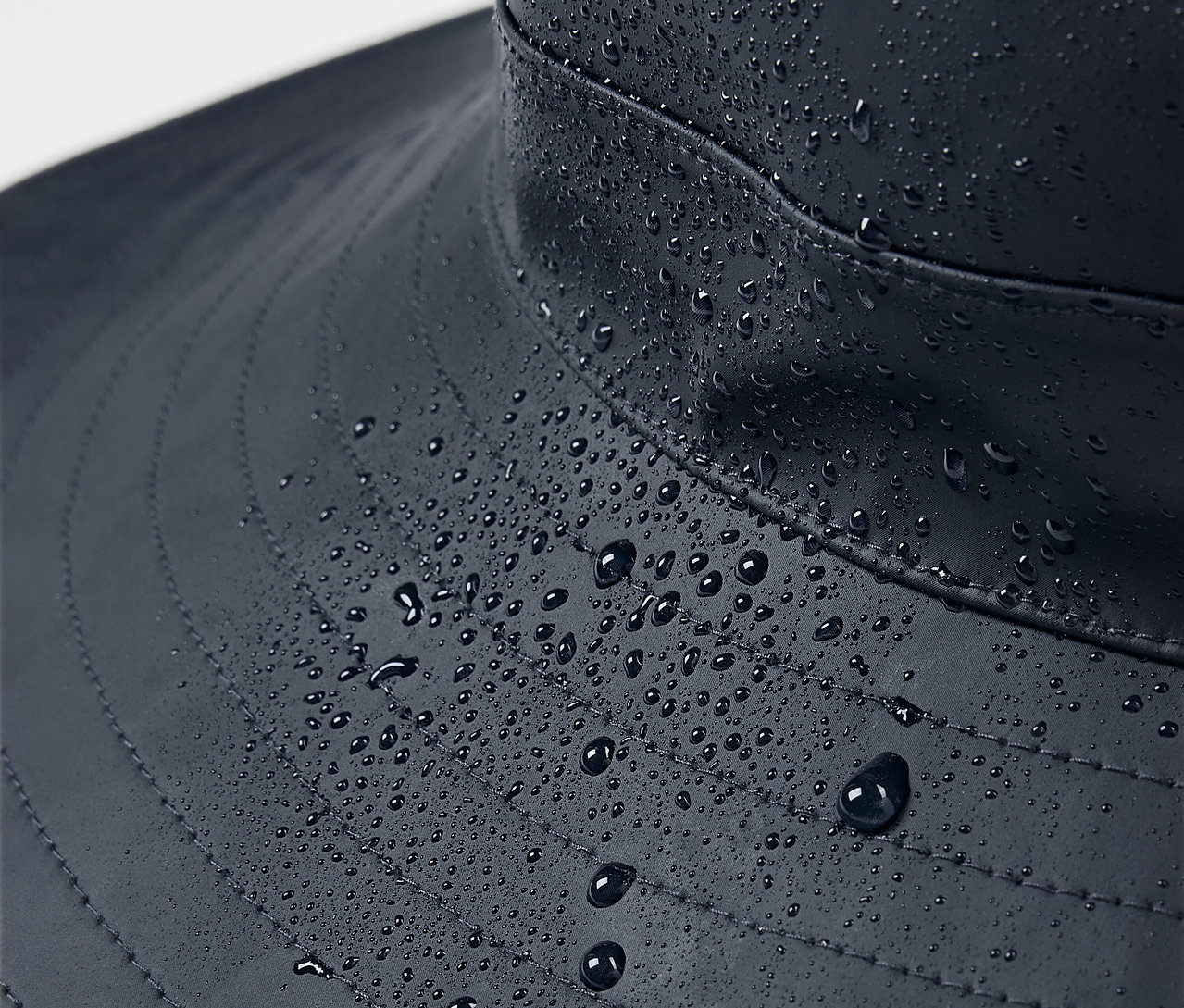 Gros plan sur un chapeau de pluie bleu avec des gouttes d'eau.